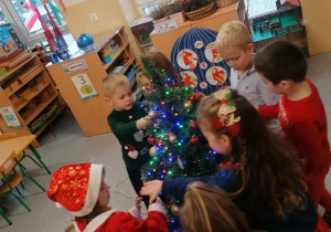 Dzieci ubierają świąteczną choinkę.